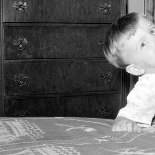 Child in light pajamas lying on a patterned bed.