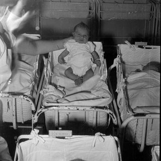 Infant in a hospital bassinet with 'Kummer' label.