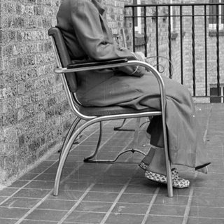 Woman in a suit sitting on a tiled terrace.