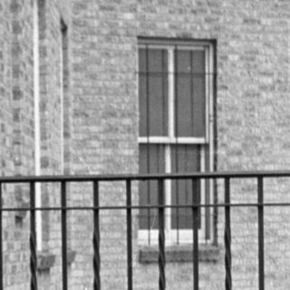 Woman in a suit sitting on a tiled terrace.