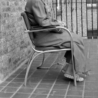 Woman in a suit sitting on a tiled balcony.