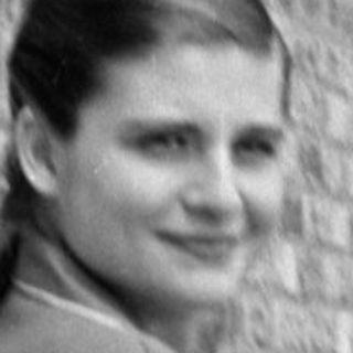 Woman in a suit sitting on a tiled balcony.