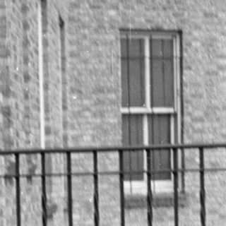 Woman in a suit sitting on a tiled balcony.