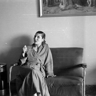 Woman in a robe sitting on a leather sofa.
