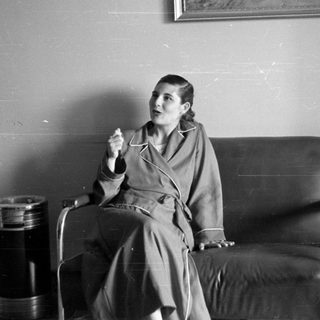 Woman in a robe sitting on a leather sofa.