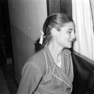 Woman standing next to a sign reading 'NURSERY'.