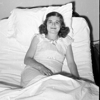 Woman in ruffled dress reclining on white pillows.