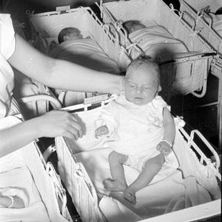 Infants in white bassinets in a nursery setting.
