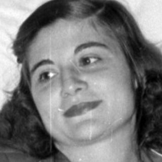 Woman in pajamas reclining on white pillows.