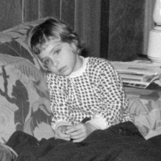 Two children lounging on a floral sofa.