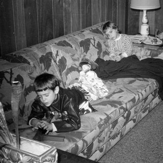 Two children lounging on a floral sofa.
