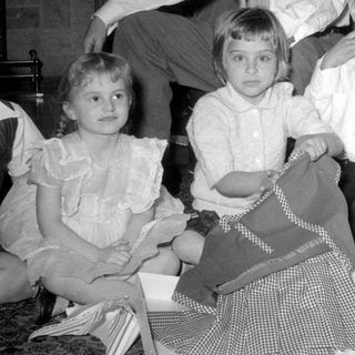 Three children and a man indoors with a gift.