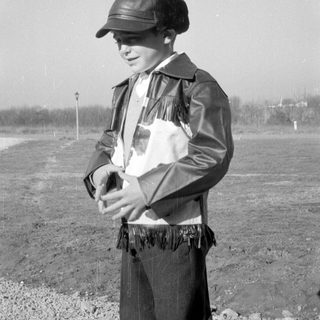 Child in fringed leather jacket and cap.