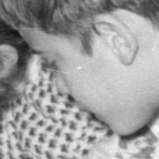 Two children opening presents on a carpeted floor.