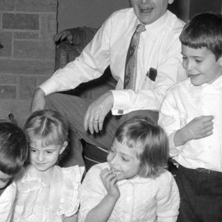 Four children and a man in a living room.