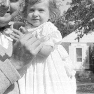 Man and young girl in white dress outdoors.