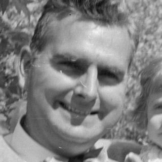 Man and young girl in white dress outdoors.