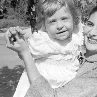 Woman and child in white ruffled dress outdoors.