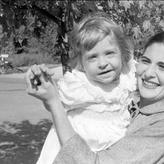Woman and child in white ruffled dress outdoors.