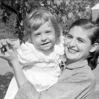 Woman and child in white ruffled dress outdoors.