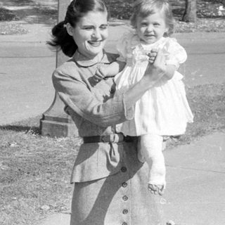 Woman holding a child in a residential neighborhood.