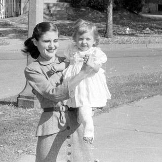 Woman holding a child in a residential neighborhood.