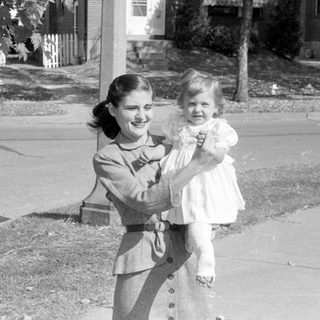 Woman holding a child in a residential neighborhood.