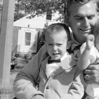 Man with two young children in a residential area.