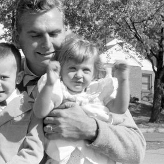 Man with two young children in a residential area.