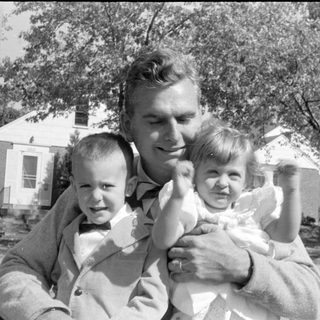 Man with two young children in a residential area.