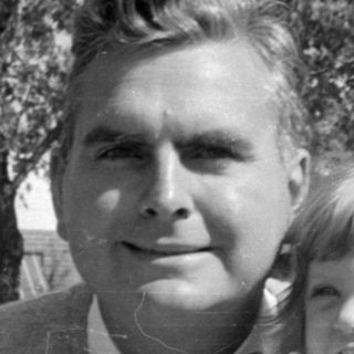 Man and two children in formal attire outdoors.