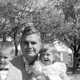 Man and two children in formal attire outdoors.