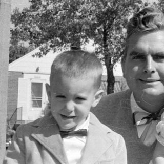Man and two children in formal attire outdoors.