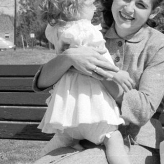 Woman and two children on a wooden park bench.