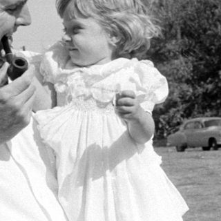 Man with pipe and girl in white dress.