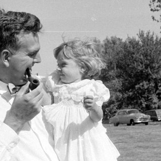 Man with pipe and girl in white dress.