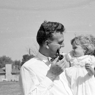 Man with pipe and girl in white dress.