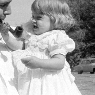 Man and young girl with a pipe outdoors.