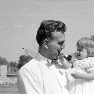 Man and young girl with a pipe outdoors.
