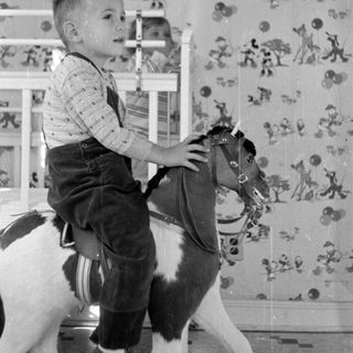 Boy on a rocking horse in a nursery.