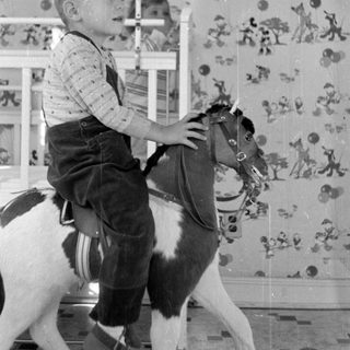 Boy on a rocking horse in a nursery.