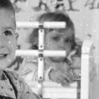 Boy on toy horse in patterned room.