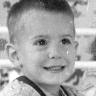 Boy on toy horse in patterned room.