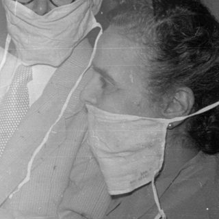 Two masked adults with a newborn baby.