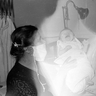 Two masked adults with a newborn baby.