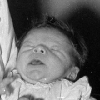 Woman in white gown holding an infant.