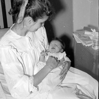 Woman in white gown holding an infant.