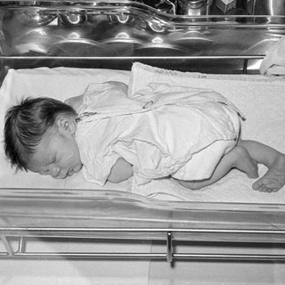 Newborn baby sleeping in a hospital bassinet.