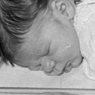 Newborn baby sleeping in a hospital bassinet.