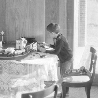 Boy playing with model train set on a table.